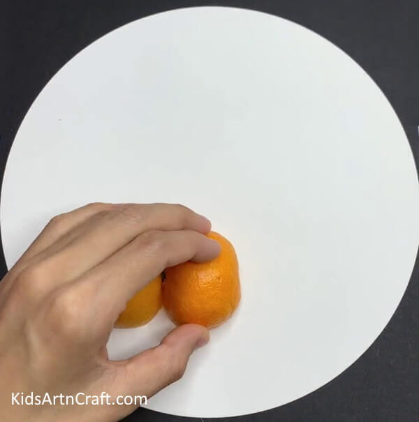 Pasting The Peel Over White Sheet - Crafting an Appealing Caterpillar from Orange Skins with Kids