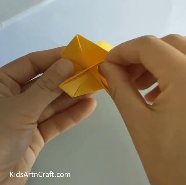 Take one of the edges and start folding the whole design- The Basics of Making a Rose from Paper - An Easy Tutorial for Beginners 