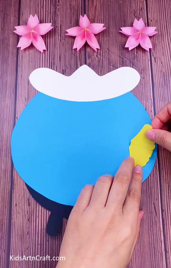 Pasting the cutout on blue paper using adhesive. Making of Aquarium craft step-by-step process for kids.