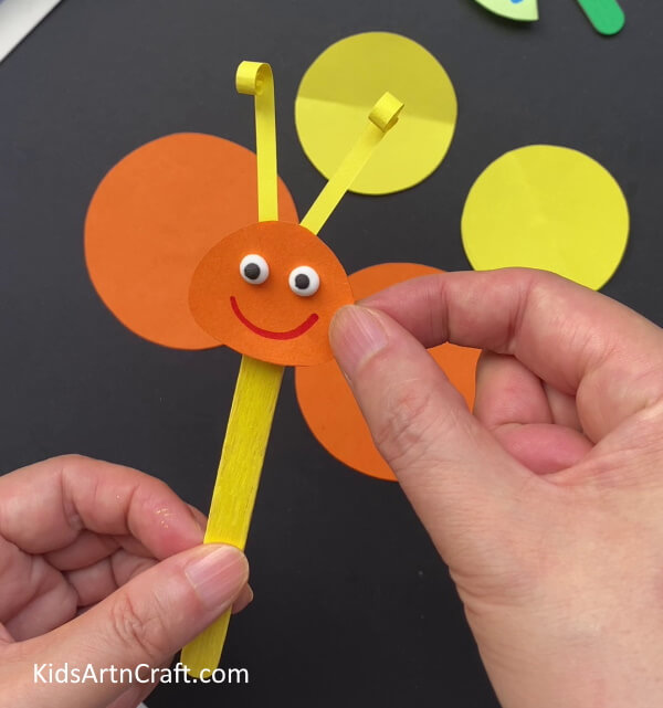 Pasting The Face Over The Stick - Learn How To Make A Paper Butterfly, Step By Step