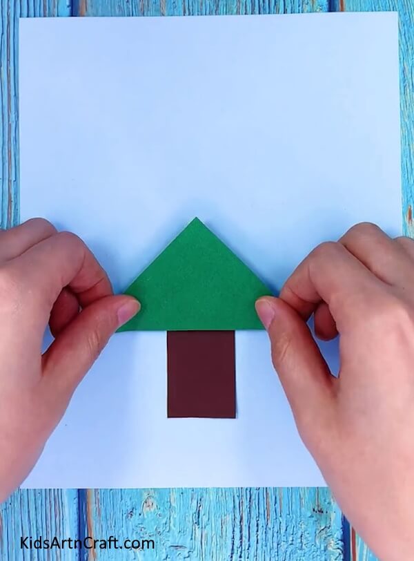Making triangle with green craft paper- Constructing a festive paper tree to adorn your space for Christmas 