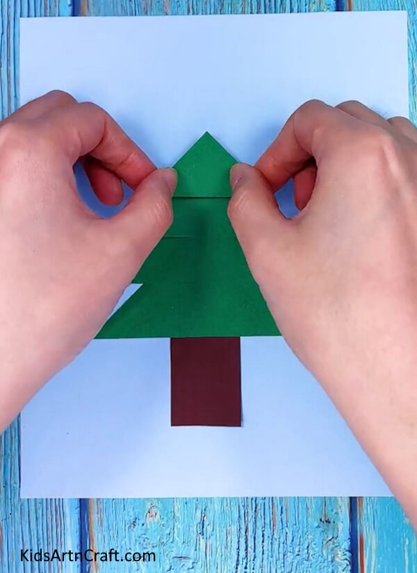 Making three more triangles with green craft paper- Crafting a Christmas tree of paper to display during the Yuletide season 