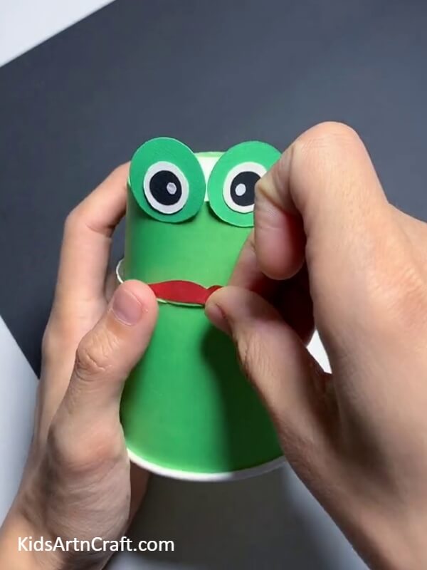 Pasting The Upper Lip-This tutorial helps kids build a frog puppet from a paper cup