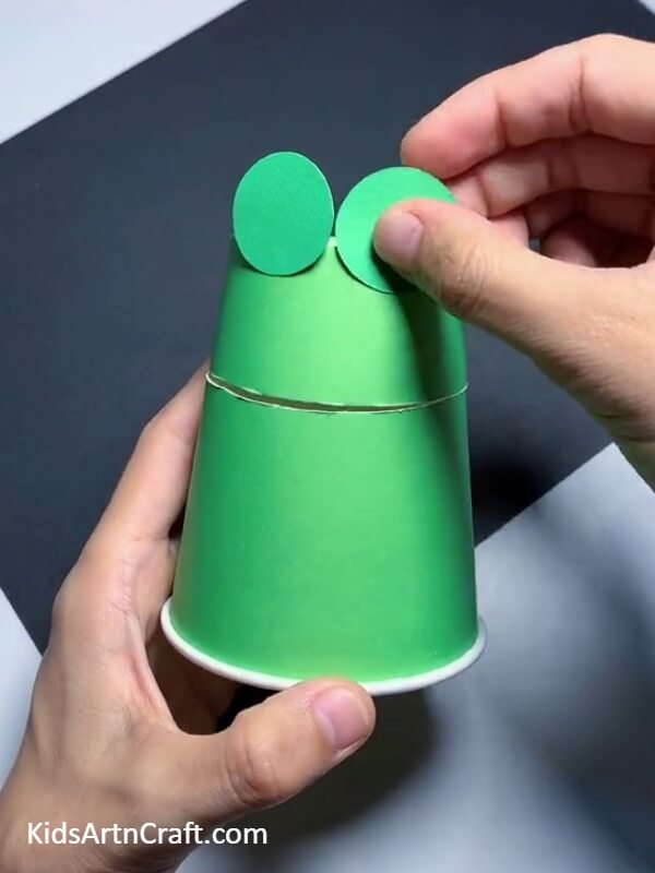 Pasting The Eye Circles-This tutorial demonstrates how to make a frog puppet from a paper cup