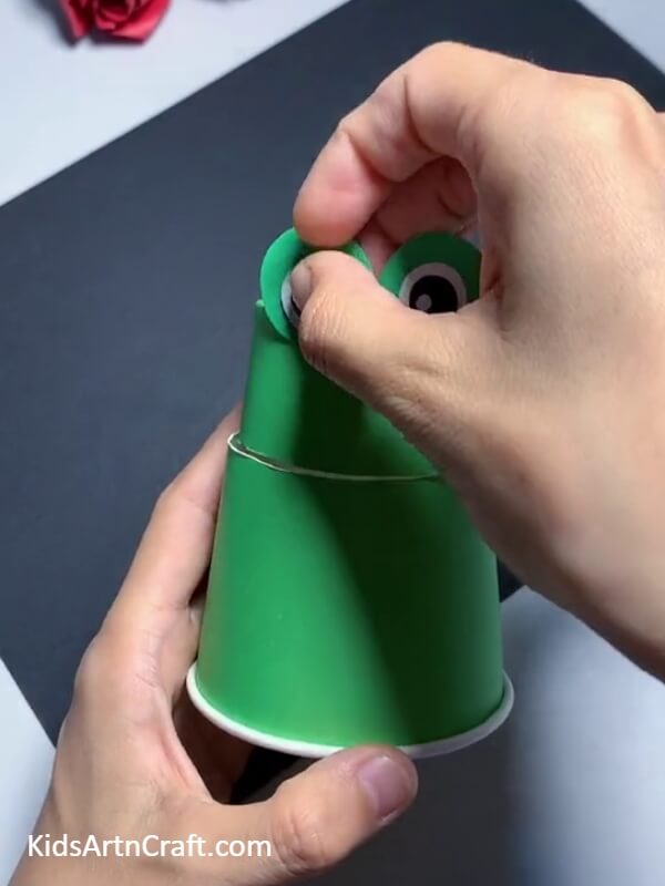 Pasting The Eyes-This tutorial will show kids how to make a frog puppet from a paper cup