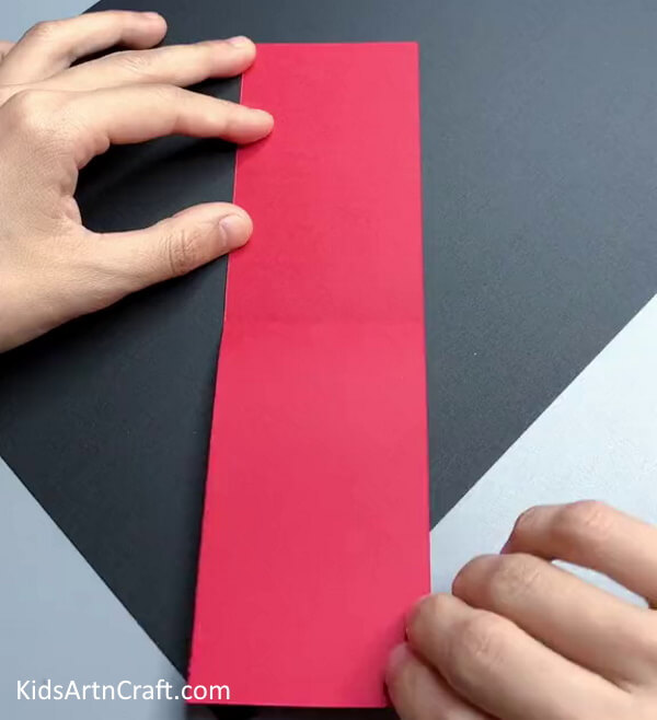 Creasing A Red Paper Strip- Constructing Dragonflies Out of Paper for Educational Purposes 