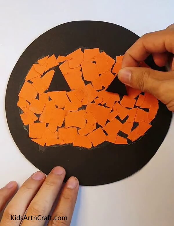 Sticking a Black Craft Paper as Eyes - Step-by-step instructions to craft a paper pumpkin