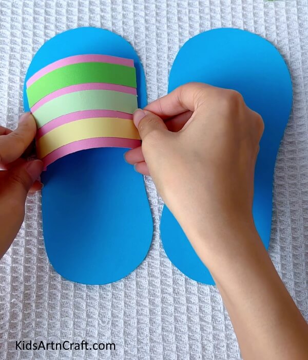 Sticking the first strap onto the slipper- Paper Slipper Crafting - An Easy Tutorial for Children