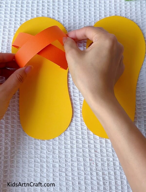 Sticking the second strip to complete the criss-cross design- How to Make Paper Slippers Easily - A Step-by-Step Tutorial for Kids
