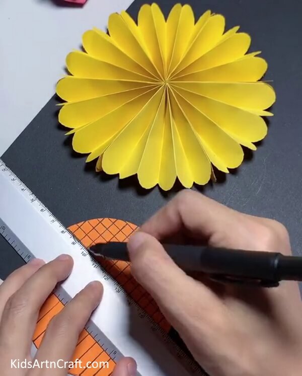 Making Vertical and Horizontal lines on an Orange Circle With a Black Marker/Sketch pen - Crafting a Paper Sunflower for children