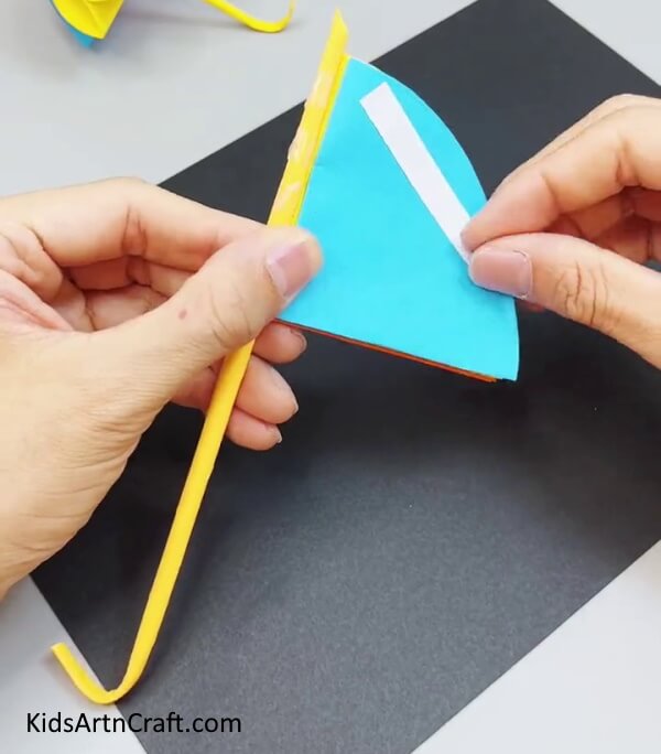 Pasting The Stick Over Quarters - Crafting a paper umbrella made easy for children. 