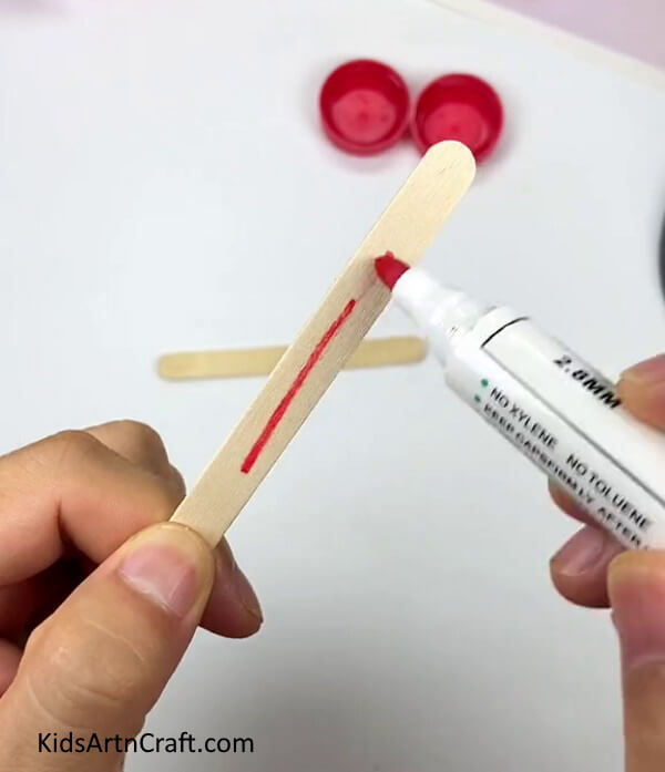 Coloring The Popsicle Stick Into Red - Making a Pinwheel with the Use of Popsicle Sticks and a Bottle Cap