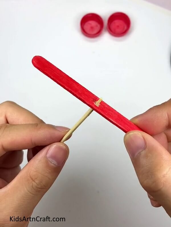 Inserting A Toothpick Into Red Popsicle Stick - Forming a Pinwheel with Popsicle Sticks and a Bottle Cap