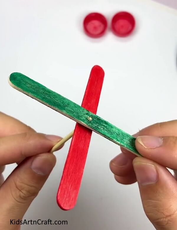 Inserting Over Another Popsicle Stick - Assembling a Pinwheel with Popsicle Sticks and a Bottle Cap