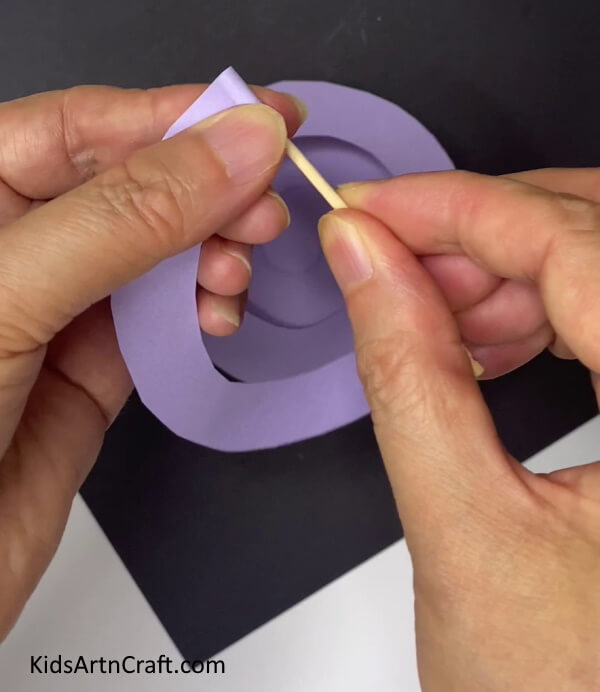 Rolling The Spiral Creating a Paper Flower of Purple Color With Leaves