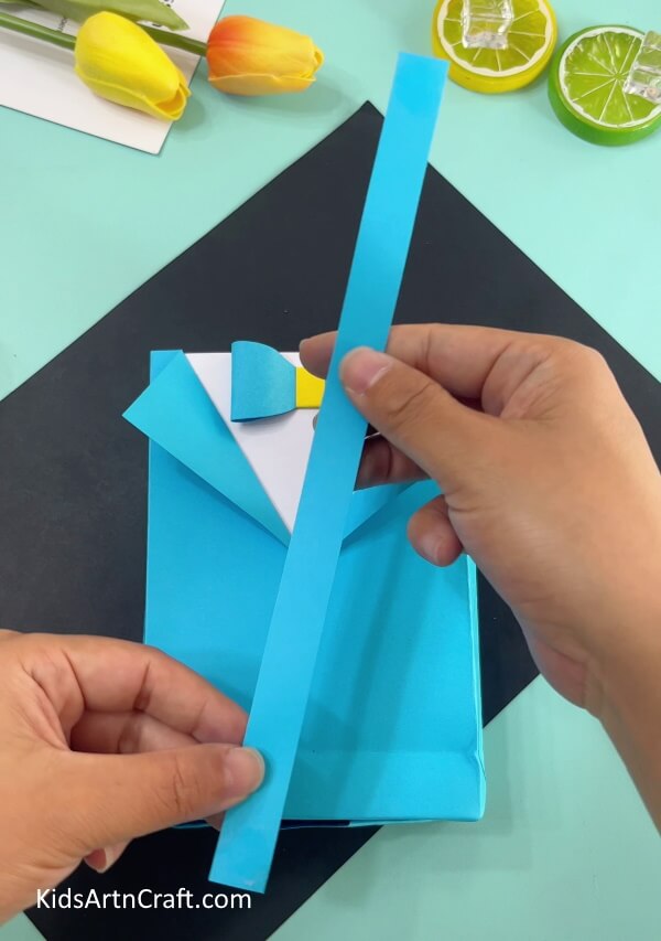 Cutting Out Blue Strip- Constructing an Origami Paper Bag with a Shirt and Bow from Home 