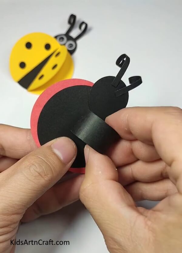 Pasting The Bug On The Ring-Here is an easy tutorial to help kids make a ladybug paper ring.