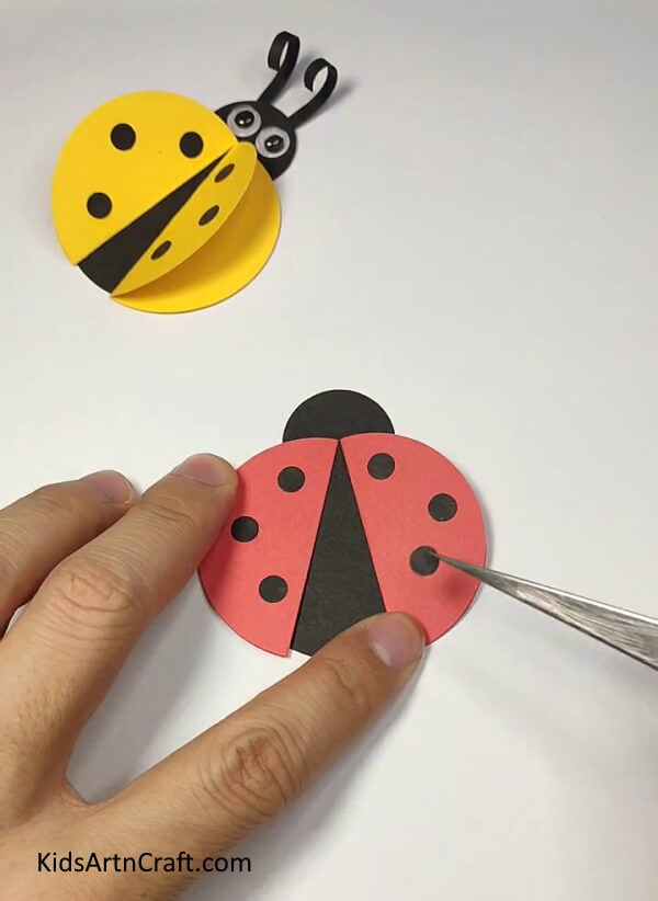 Pasting Tiny Circles On The Red Circles-Guide for kids to easily create a ladybug paper ring.