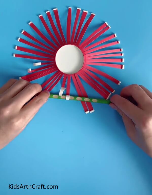 Folding The Strips-Assist your children in constructing a Paper Cup Flower Craft
