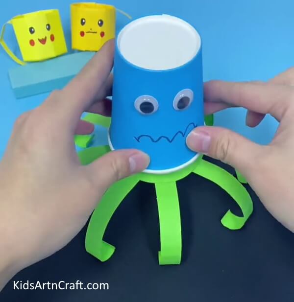 Place the cup on the stripes cutout- Help your toddler create a paper cup octopus.