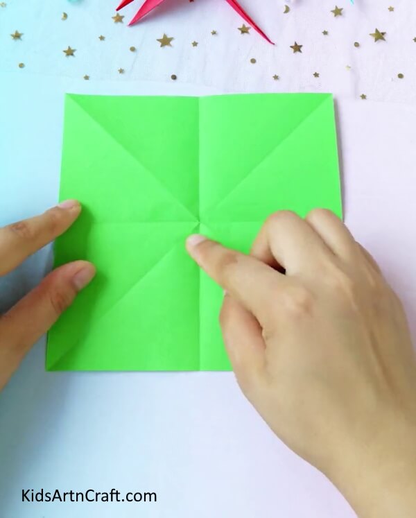 Creasing A Green Origami Paper- Step-by-step instructions for creating a dragonfly out of origami paper for children.