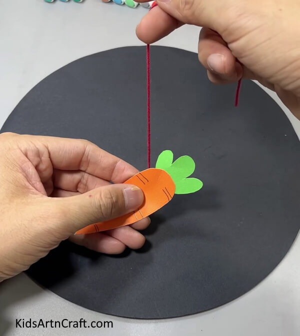 Pasting The Hourglass Paper On The Carrot -This craft requires paper to make a hanging bunny and carrot.