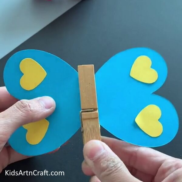Securing The Hearts With A Wooden Clothespin - Crafting paper butterflies: An activity for kids.