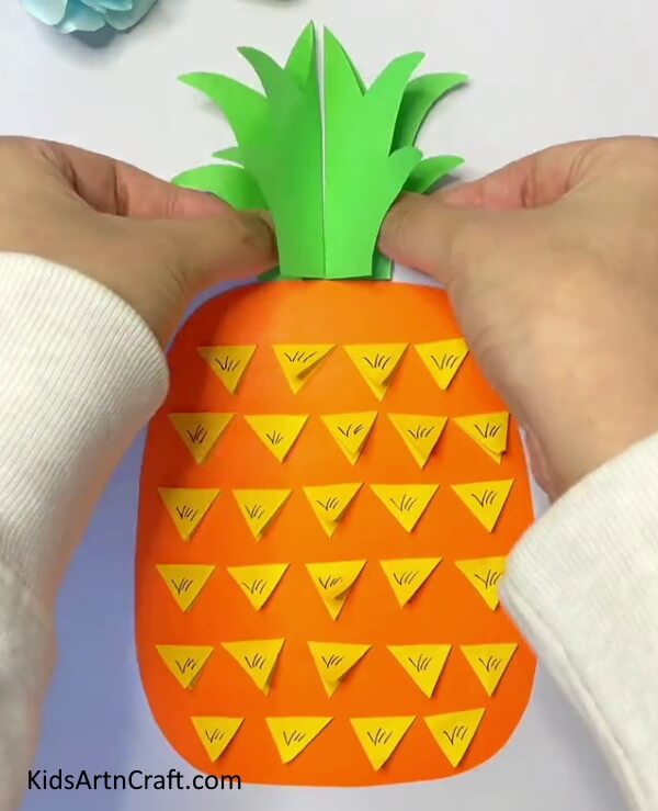 Stick The Green Leaf Above Orange Craft Paper with your hand Paper Craft- A straightforward guide to constructing Pineapple Paper Art for kids 