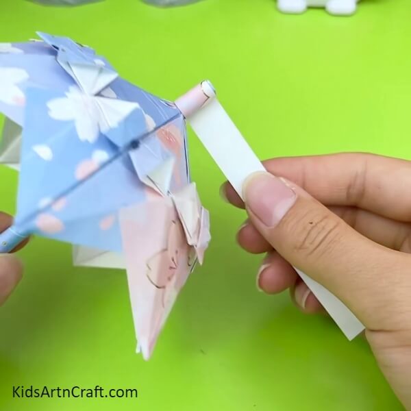 Roll Another Printed Craft Paper On The Top Of The Stick to Creative Craft Tutorial For Kids- An Artistic Origami Umbrella Crafting Guide For Kids 