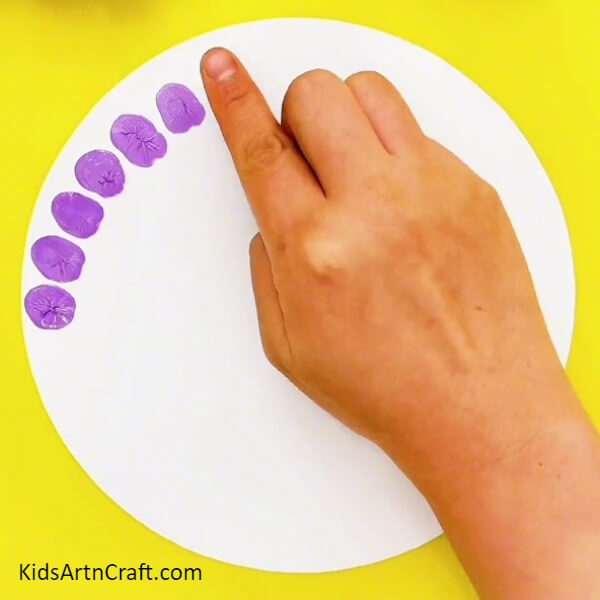 Dip your index finger in purple paint and form impressions on a white sheet- Adorable Fingerprint Art Project For Children Featuring a Peacock