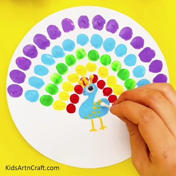 Dip a cotton bud in yellow paint and make a design on the peacock- Fun Fingerprint Artwork Of A Peacock For Kids