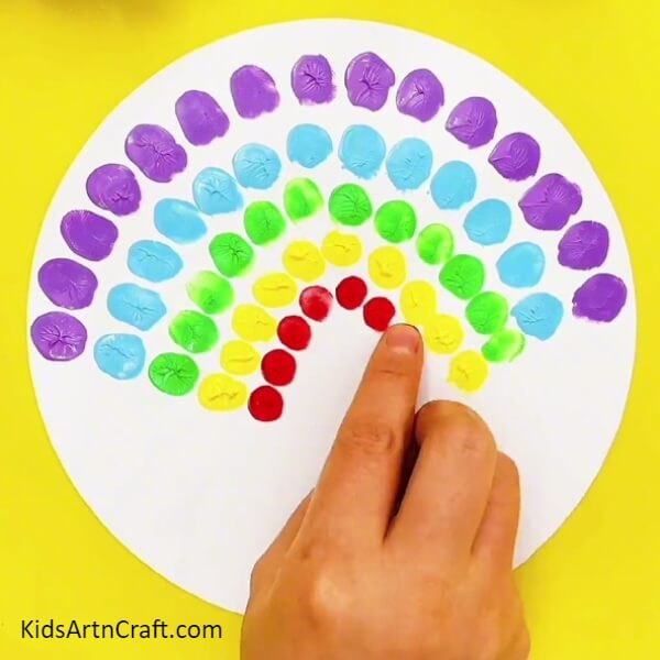 Dip the tip of your index finger and make circle on the white sheet as shown below- Creative Peacock Finger Impression Art For Little Ones