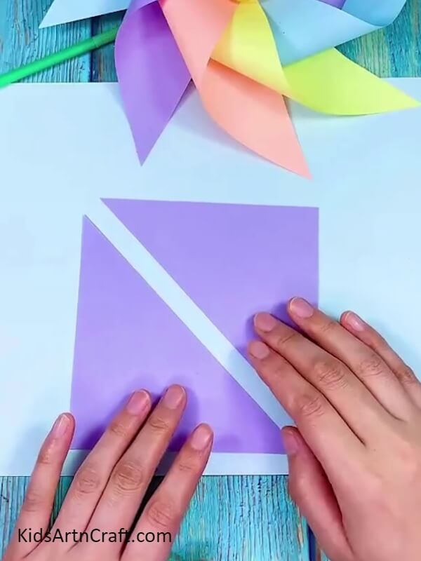 Cutting Violet Color Paper in Triangle Shape- A Guide to Crafting a Rainbow Paper Windmill for Newbies 