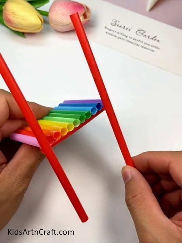 Pasting red color straw to create chair leg- Directions for Assembling a Rainbow Straw Chair for Rookies 
