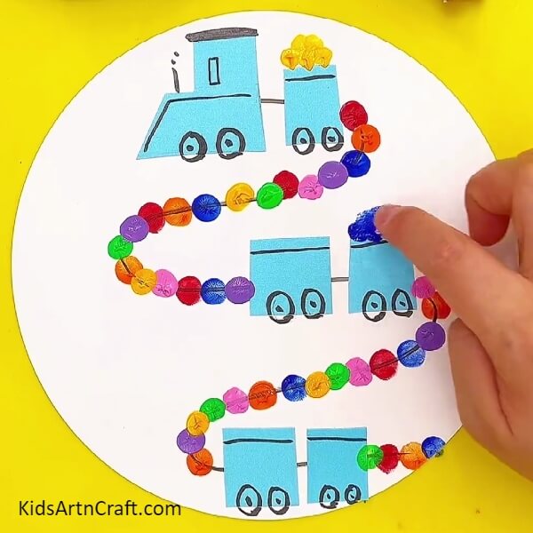 Adding goods to the trains using paints- Directions for producing a train craft with children 