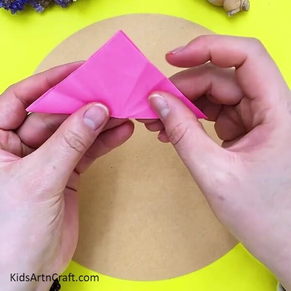 Folding our pink square paper into half- A How-To for Crafting 3D Flowers with Kids 