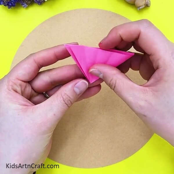 Folding pink paper one more time- Learn How to Make 3D Flowers with this Kid-Friendly Tutorial 