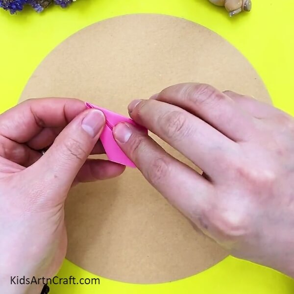 Folding both ends of pink paper inside- Crafting 3D Flowers: A Step-by-Step Tutorial for Kids 