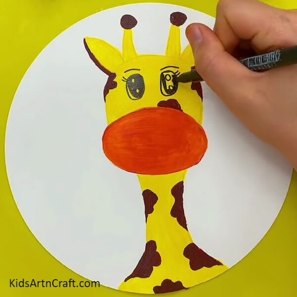 Drawing The Giraffe's Eyes With The Use Of A Black Sketch Pen- A wonderful Giraffe face painting concept for those with little experience
