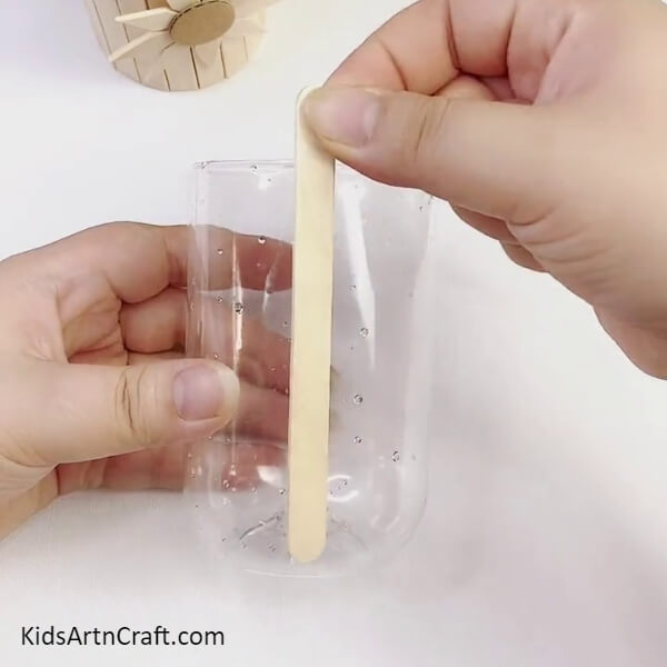 Pasting A Popsicle Stick On The Bottle Cut-out-Fun and Easy Sunflower Stand Craft Using Popsicle Sticks for Children 