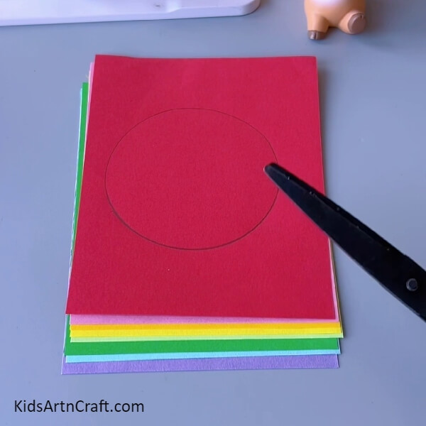 Taking scissor and cutting the outline over sheet- Step-by-step guide to create a beautiful colourful paper craft for Kids