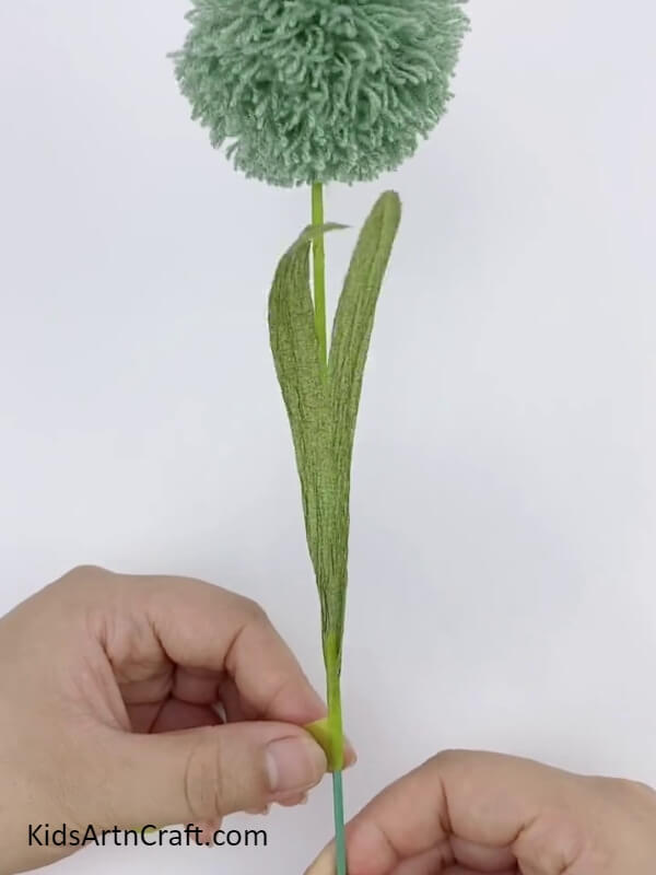 Securing The Leaves- Learn to make Pom Pom Flowers with this tutorial, using colorful threads.
