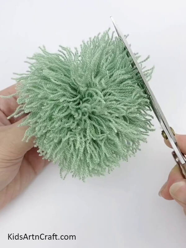 Even Out The Ends Of The Pom Pom- This tutorial is all about crafting Pom Pom Flowers with colorful threads for kids. 