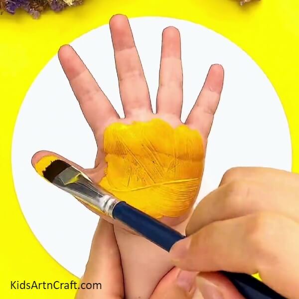 Applying Yellow Paint On The Palm-Inventive Giraffe Handprint Art Design For Novices-