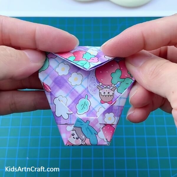 Folding The Top Corner Of The Pentagon-Create a tiny origami paper holder with the help of this tutorial