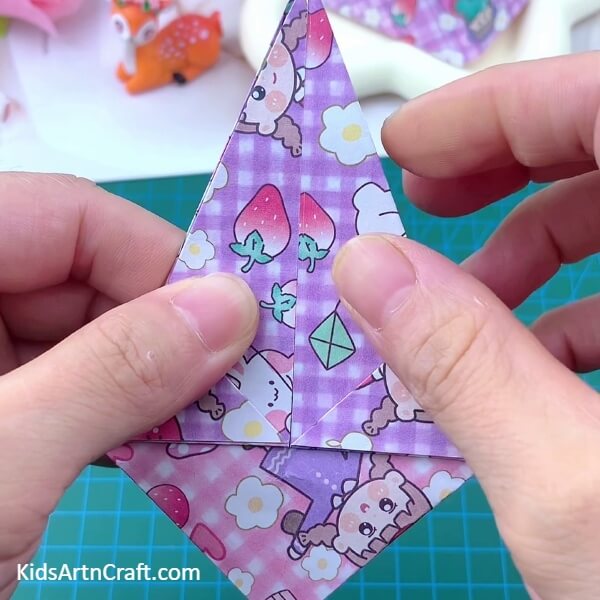 Folding the other side of paper into the middle- Crafting a Paper Basket Origami is simple with this tutorial created especially for kids.