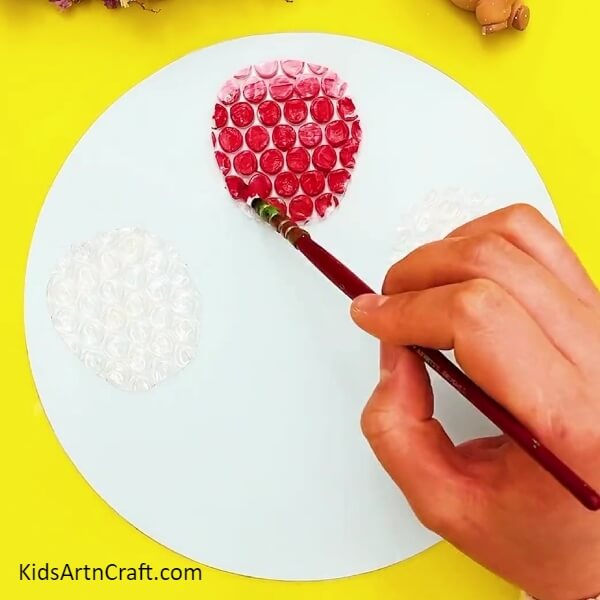 Painting Red Color On Bubble Sheet Completely- Crafting a bubble wrap octopus - guide for children