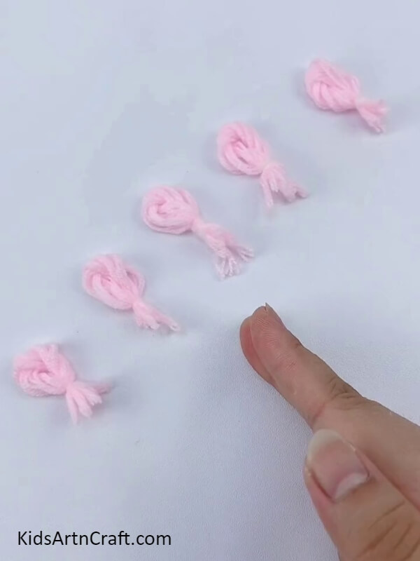 Make five more twisted knots- A craft tutorial for kids to make a wonderful flower wreath with cardboard and wool.