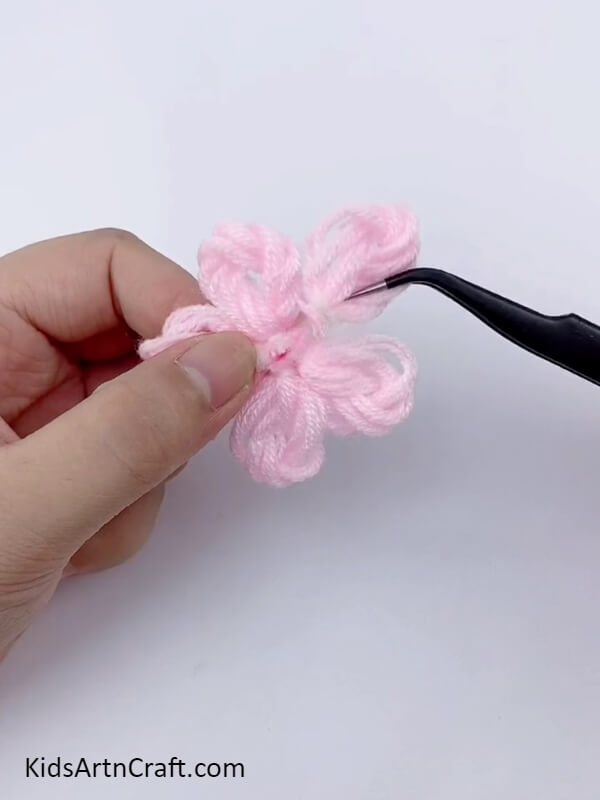 Stick all five pink wool petals on small piece of white cardboard- Detailed instructions on constructing a delightful floral wreath with cardboard and wool for young ones. 
