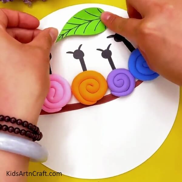 Pasting A Leaf- A clay-paper craft project for children with snails sitting atop a tree branch. 